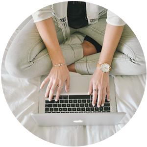 pessoa sentada em um colchão de pernas cruzadas usando um laptop